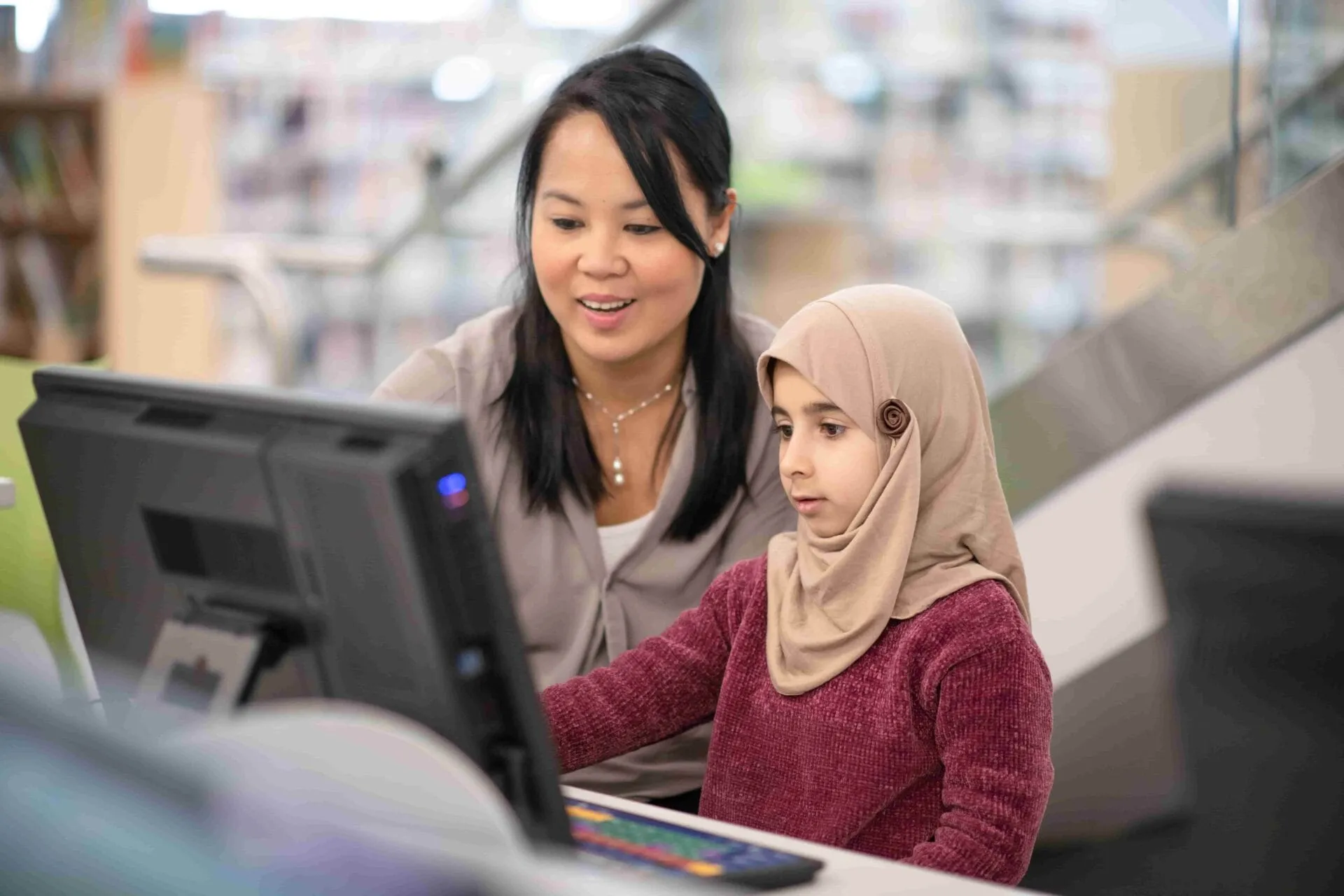 A smiling therapist assists a student at a computer