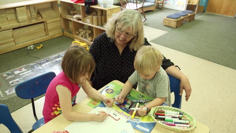 Two children playing with their grandmother in a preschool