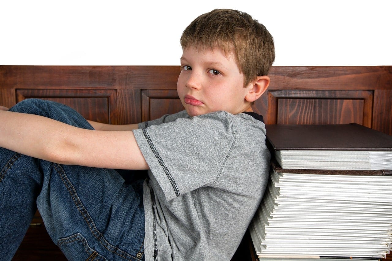 Student sitting against a stack of books
