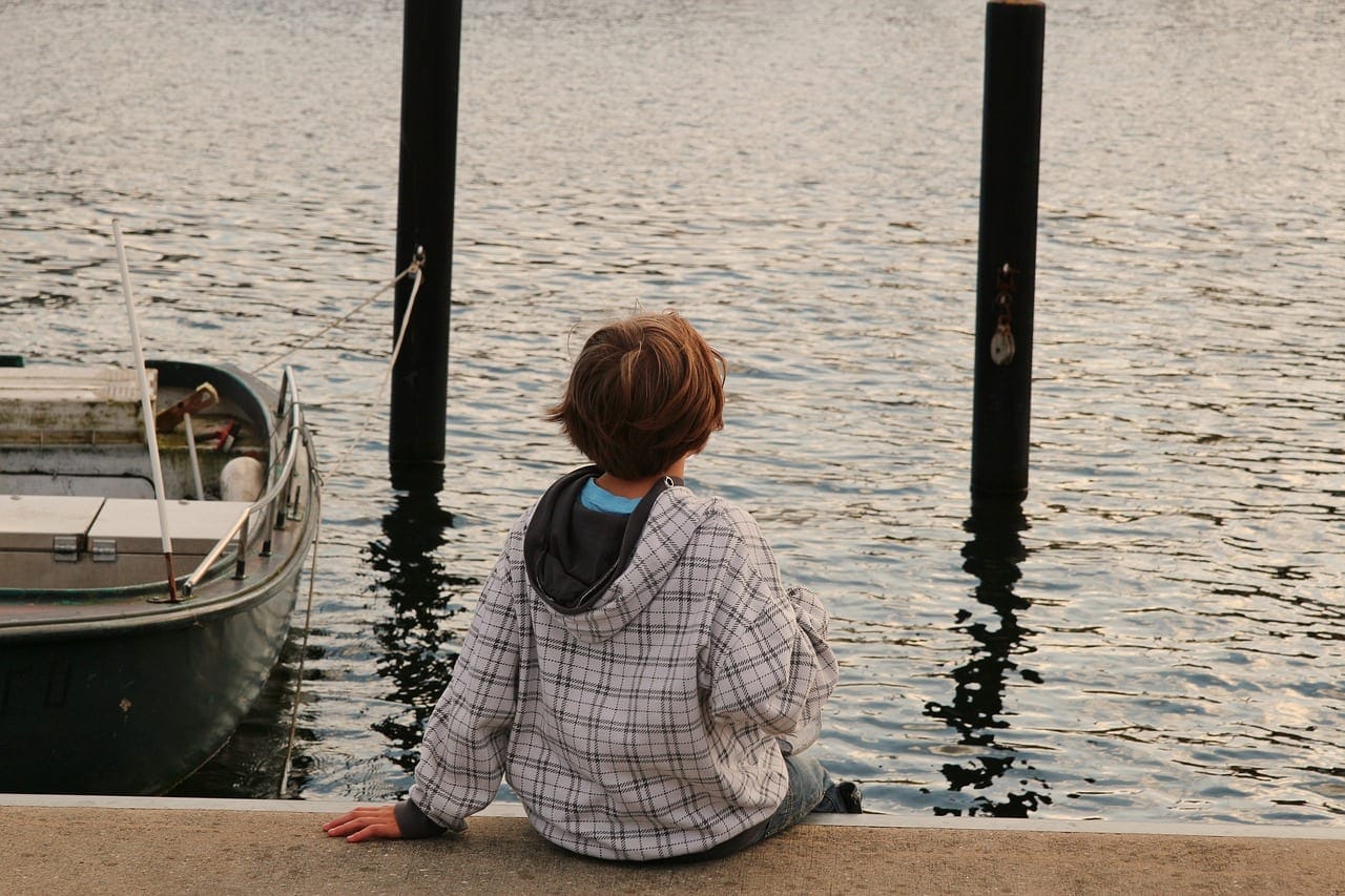 Student sitting by the water, reflecting in a serene setting