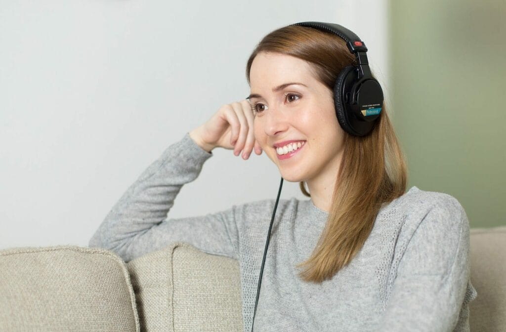 teletherapist smiling while wearing headphones, engaging in online therapy session