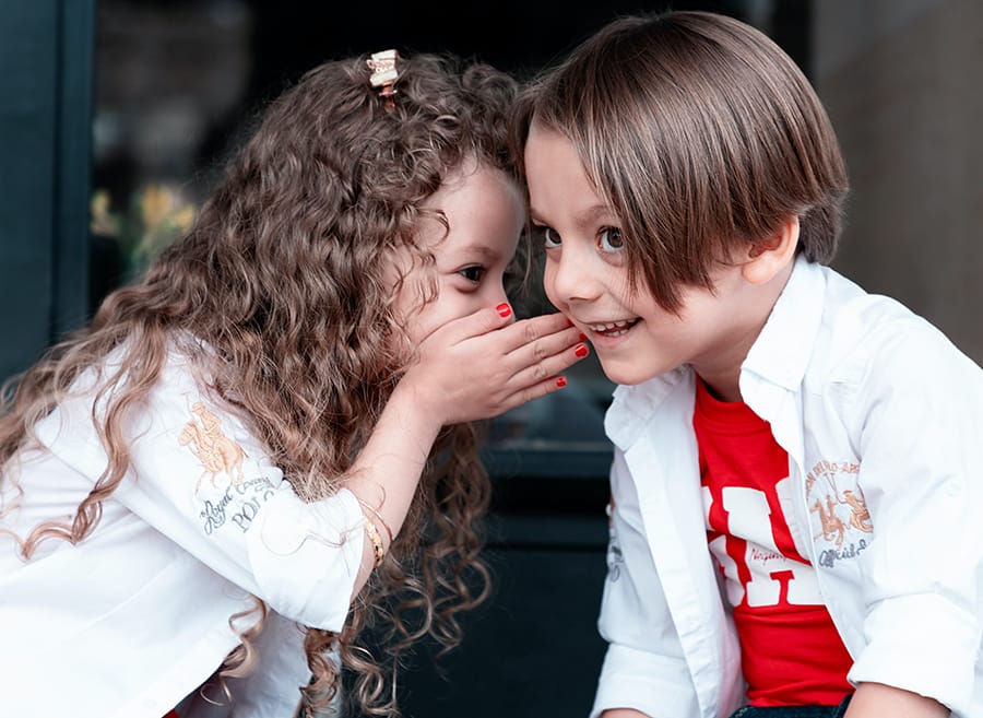 Children sharing a secret, highlighting expressive language development
