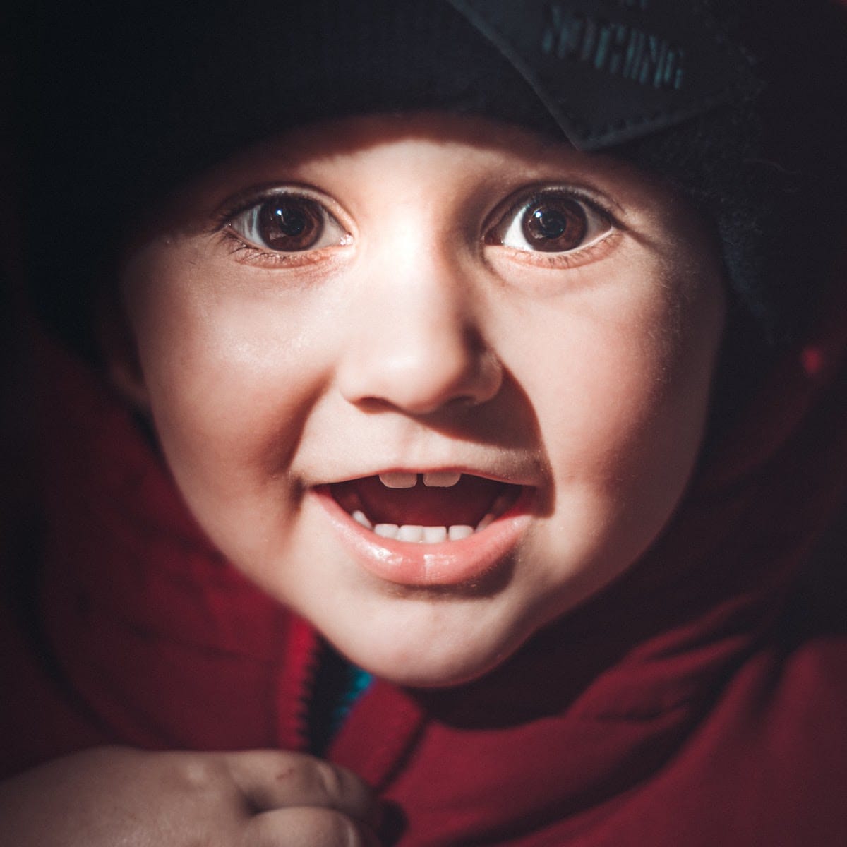 Happy boy smiling in a red jacket and hat