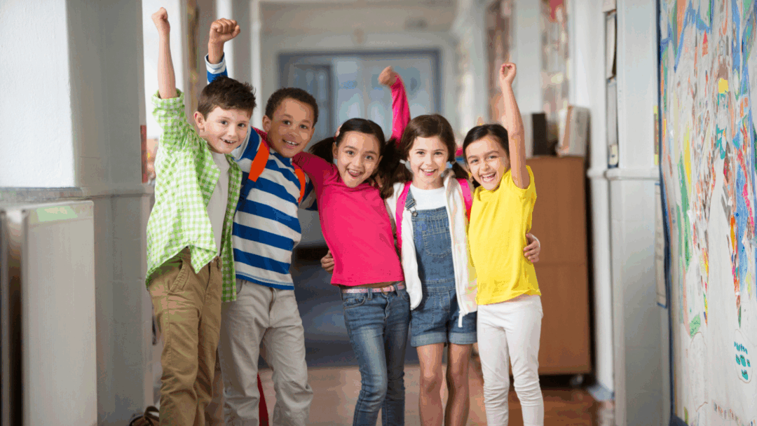 Diverse group of joyful students celebrating in school hallway