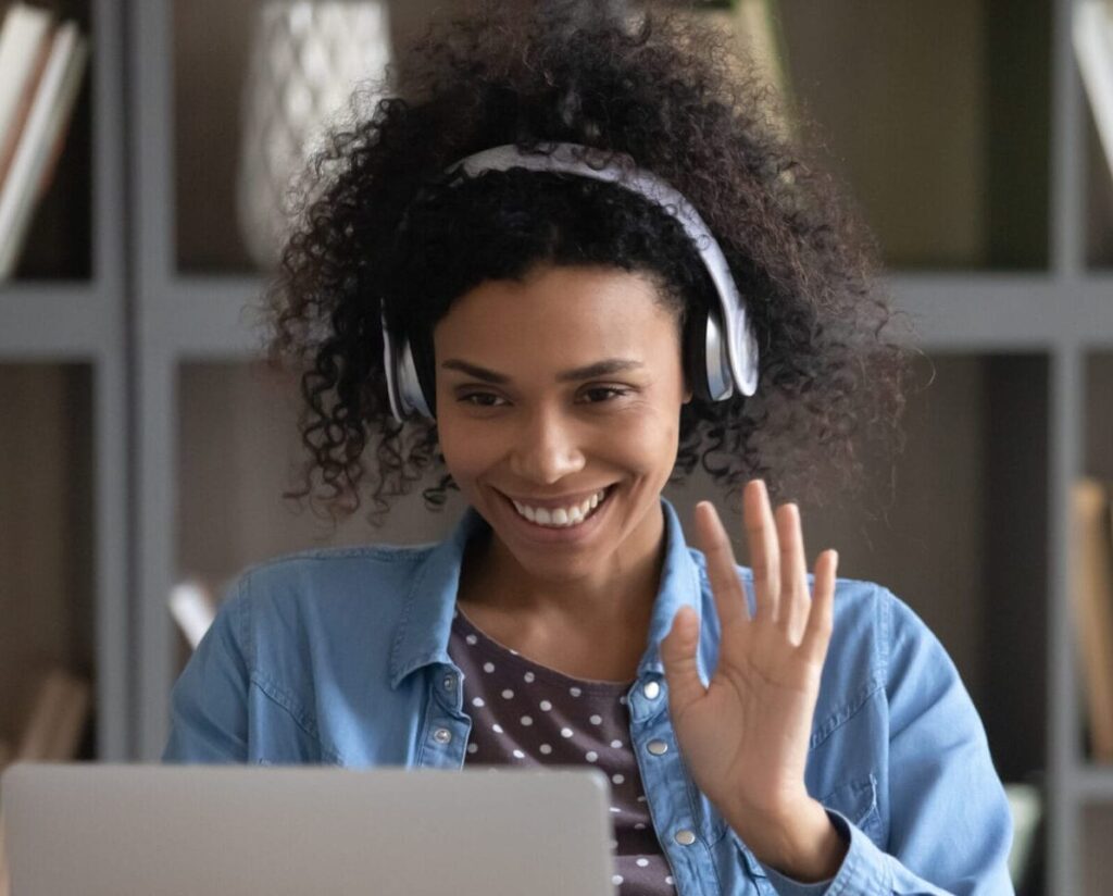 Smiling teletherapist engaging with online therapy tools on laptop