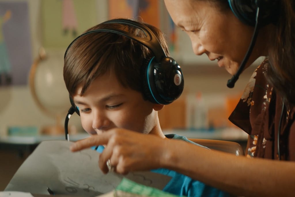 Young student and teacher wearing headphones work together while connected to a virtual classroom