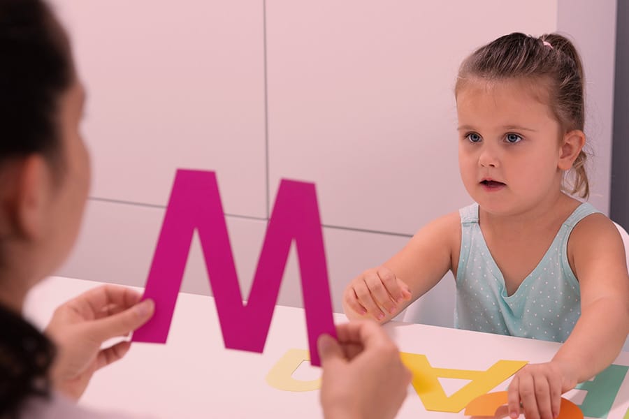 Student working with a therapist using colorful letter cards