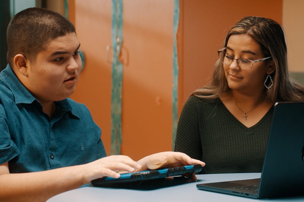 Student engaged in therapy session with therapist using technology