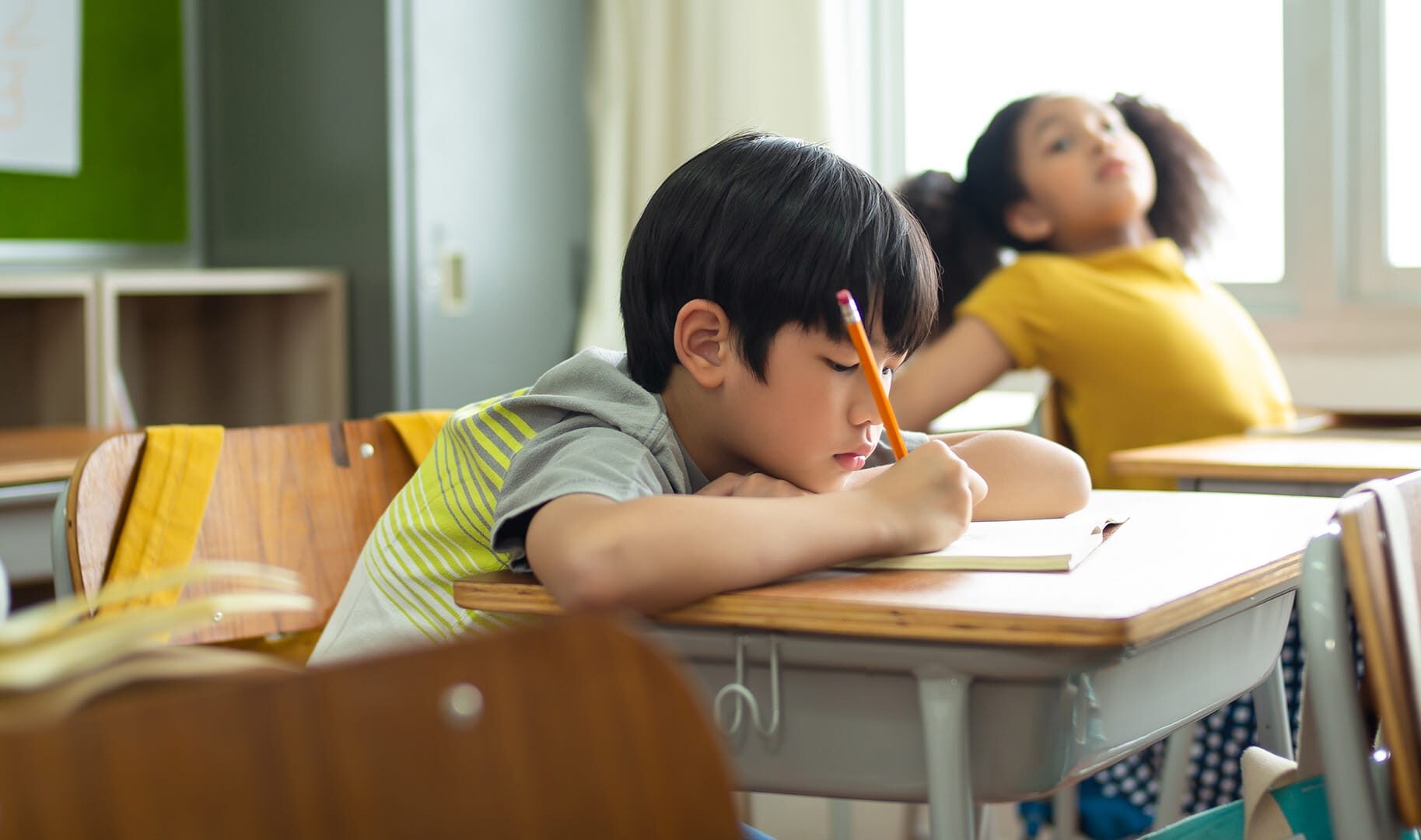 A student resting on a desk in a classroom setting