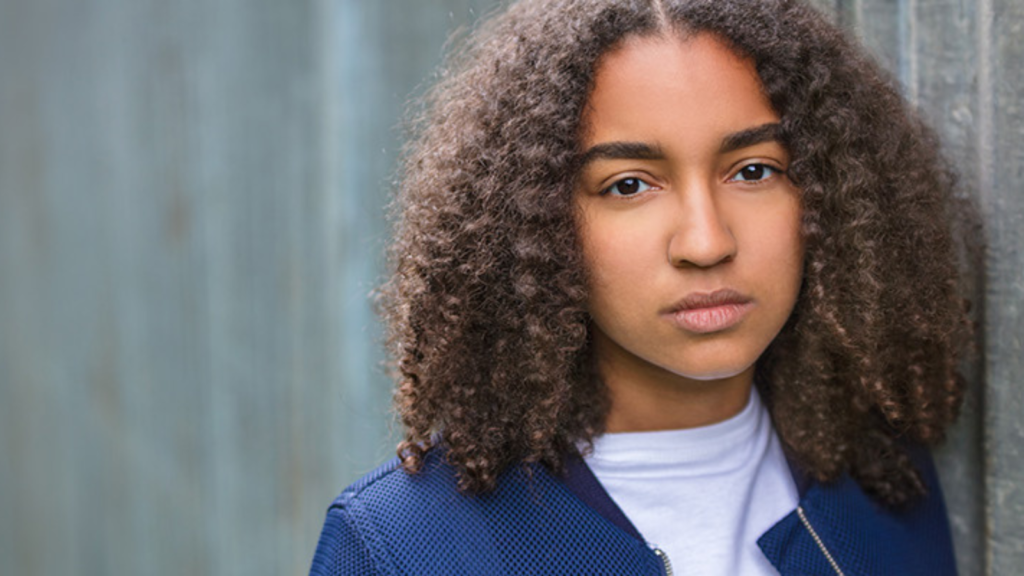 A student with curly hair against a backdrop